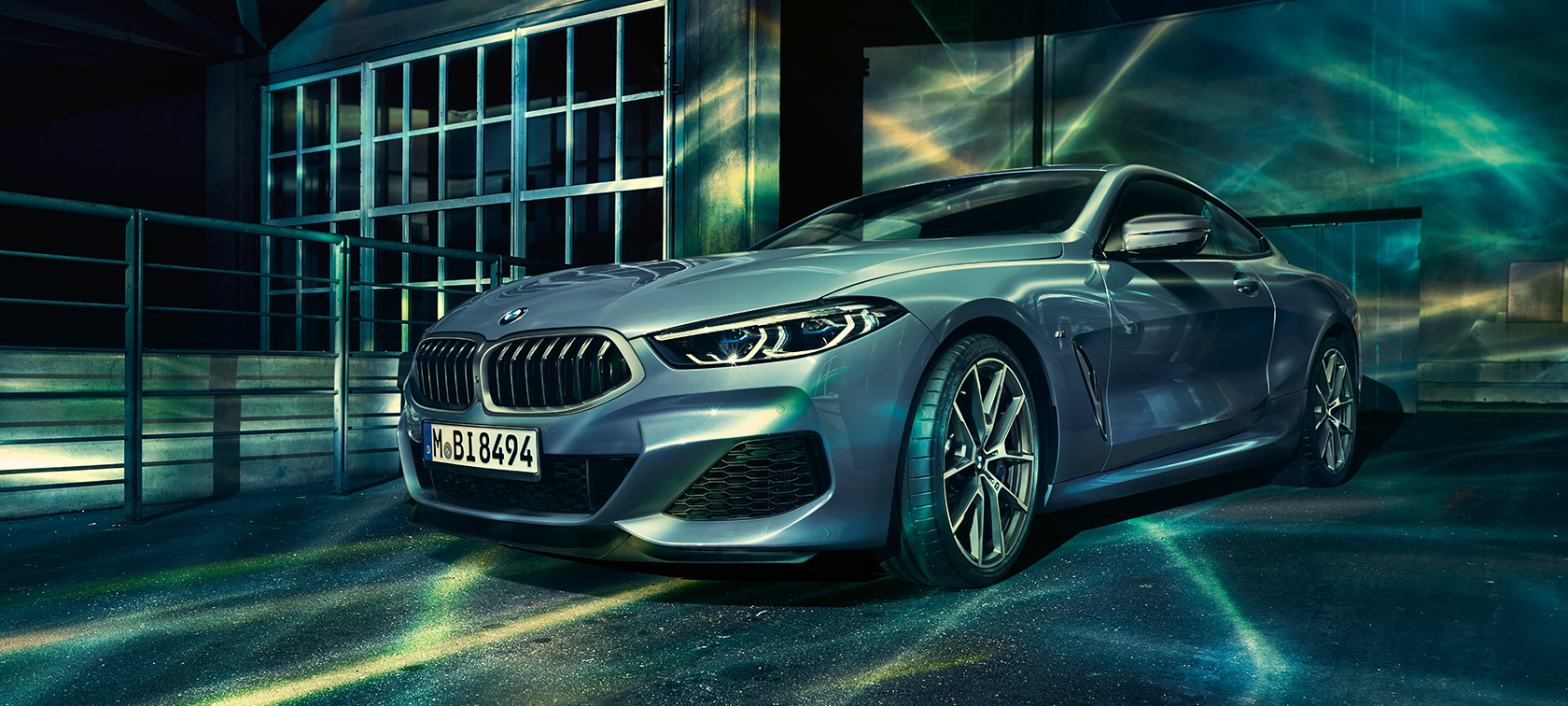 The BMW 8 Series Coupé, three-quarter front shot, in front of industry building.