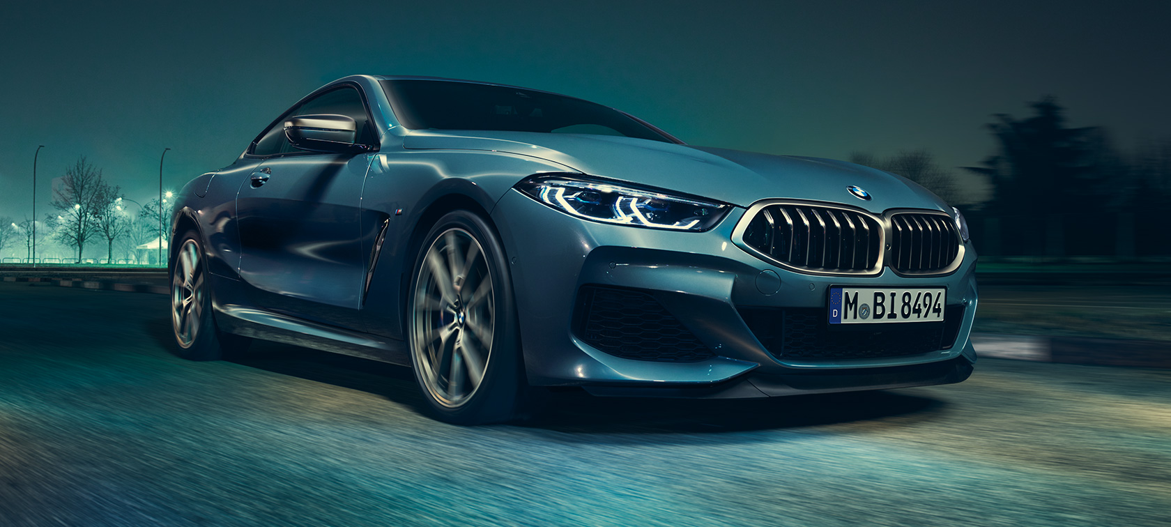 BMW M850i xDrive Coupé in Barcelona Blue metallic driving, three-quarter front view.